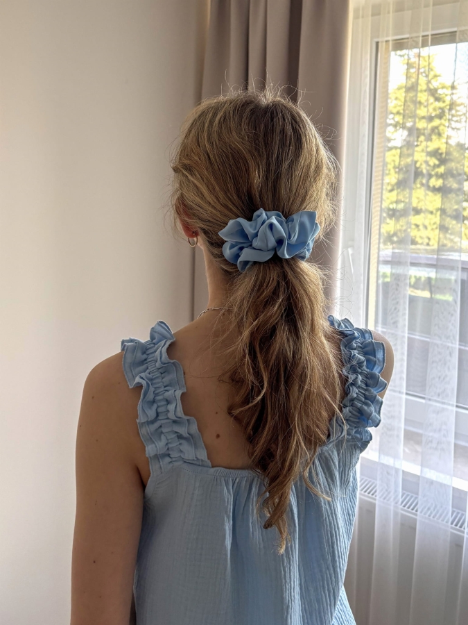 Błękitna scrunchie z satyny prezentowana na włosach