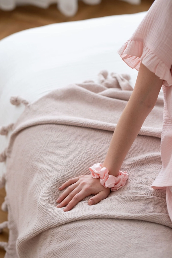 Pudrowo różowa satynowa gumka do włosów scrunchie na ręce