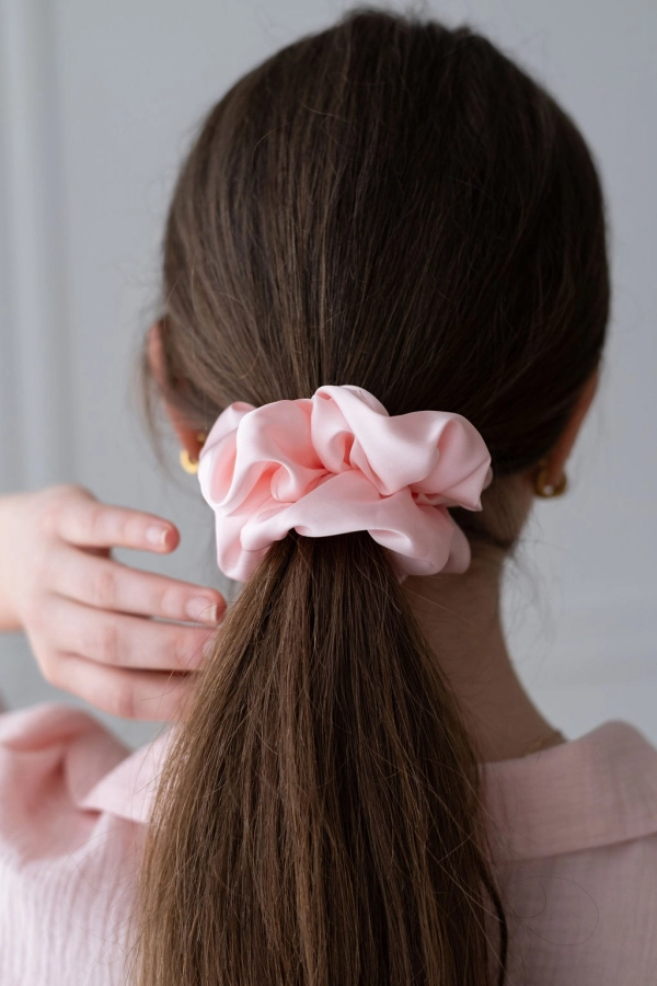 różowa scrunchie z satyny prezentowana na włosach