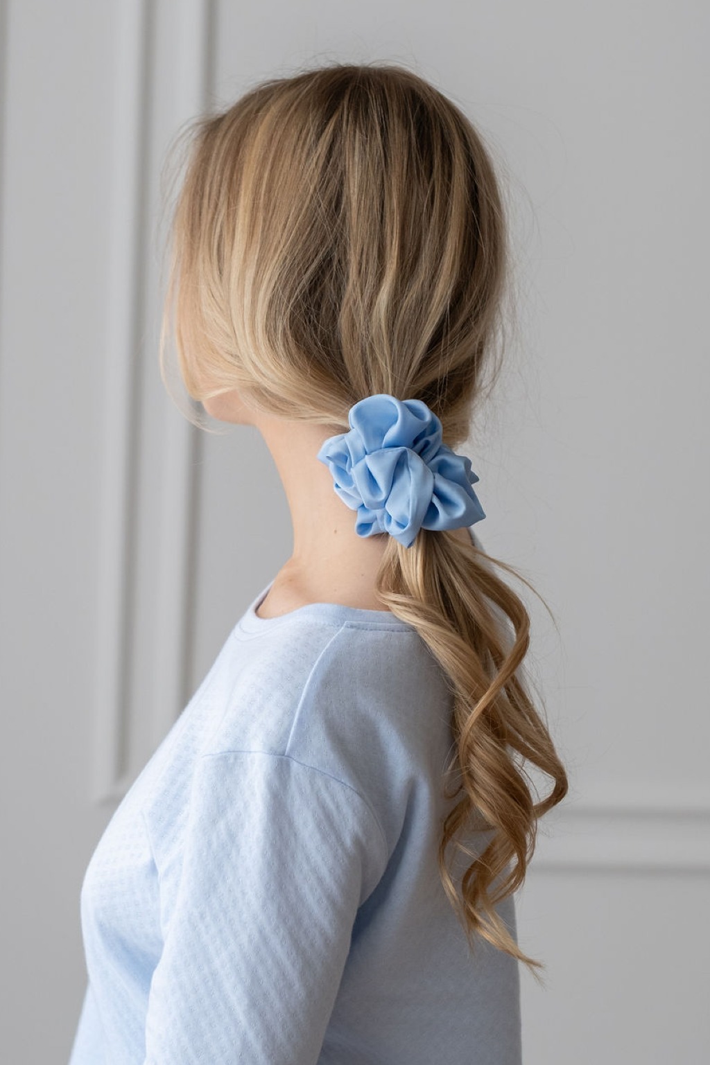 Błękitna scrunchie z satyny prezentowana na włosach modelki