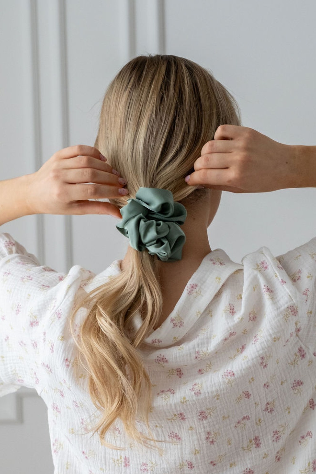 Zielona scrunchie z satyny prezentowana na włosach